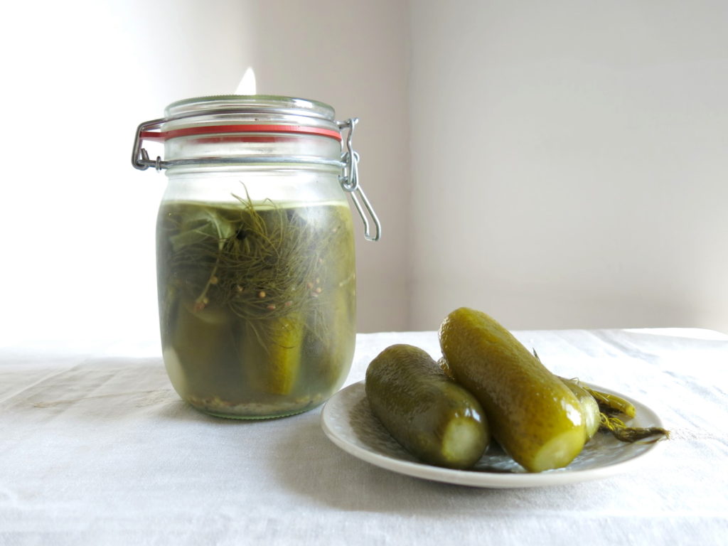 Fermentierte Salzgurken im Glas und auf einem Teller