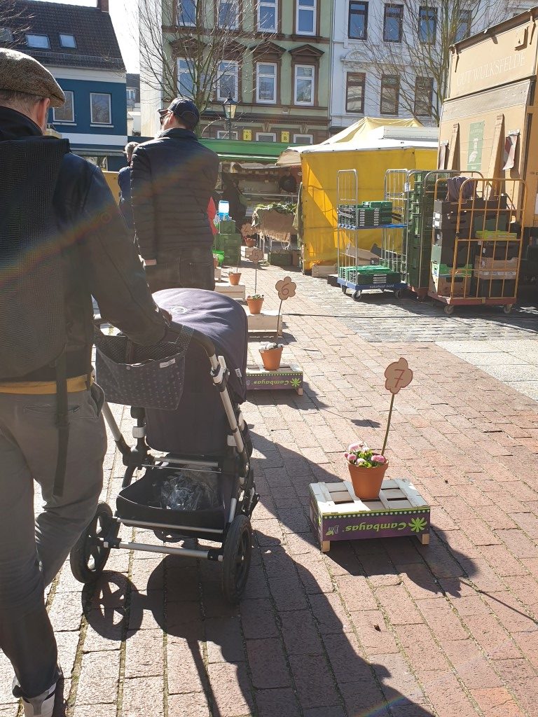 Wochenmarkt mit Schlange und Markierungen für Corona-Abstand